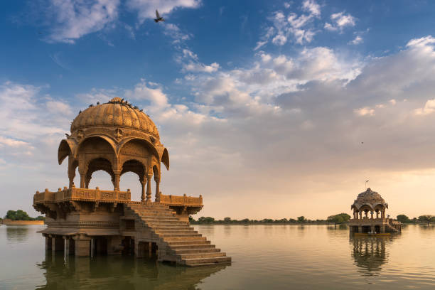 Chhatris and shrines of hindu Gods and goddesses at Gadisar lake, Jaisalmer, Rajasthan, India with reflection on water. Indo-Islamic architecture , sun set and colorful clouds with Gadisar lake. stock photo