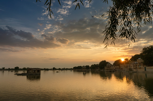 Beautiful sunset at Gadisar lake, Jaisalmer, Rajasthan, India. Setting sun and colorful clouds in the sky with view of the Gadisar lake. Connected with Indira Gandhi Canal for continuous water supply.