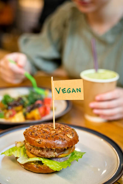 Woman eating veggie burger in a vegan cafe or restaurant stock photo