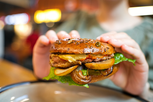 istock Woman eating veggie burger in a vegan cafe or restaurant 1480629036