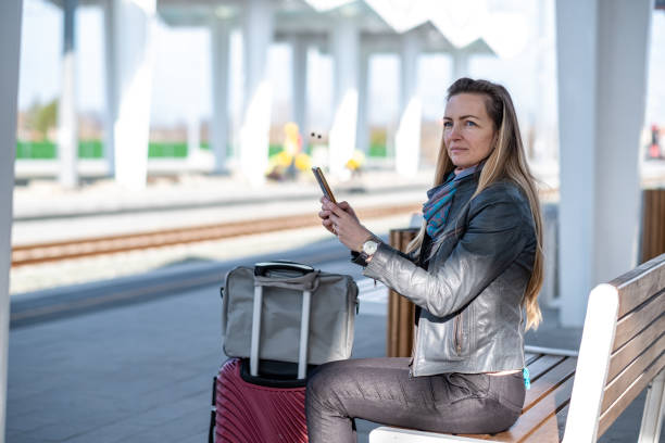 istock a woman is waiting for a train with a phone 1480629221