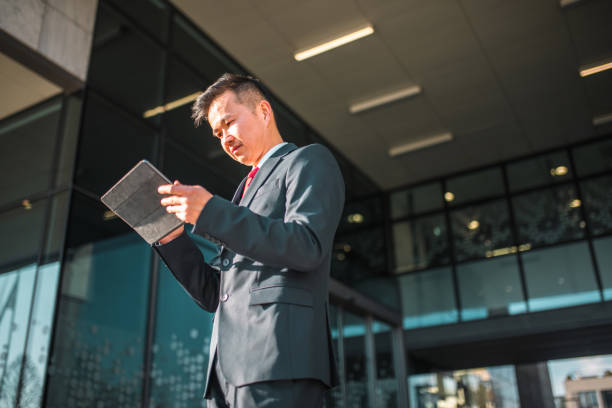 Chinese Businessman Using Digital Tablet In A Business District