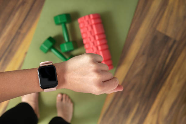 nahaufnahme einer frau, die eine smartwatch gegen fitnessgeräte auf dem boden trägt - checking the time watch women looking stock-fotos und bilder