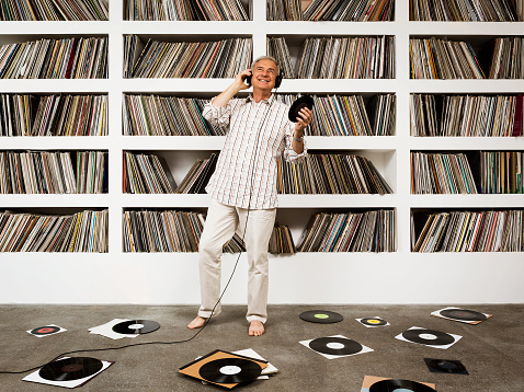 A mature man listening to vinyl records and dancing.