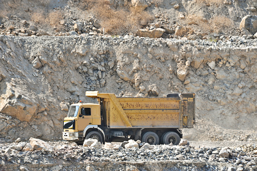 iron ore quarry dump truck moves on the road of stepped terraced terrain