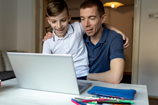 Father and son studying with laptop on a online class at home