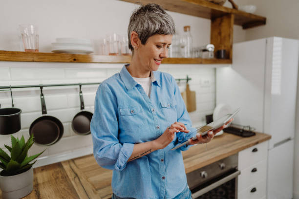 istock Senior woman standing and holding her digital tablet 1480641654