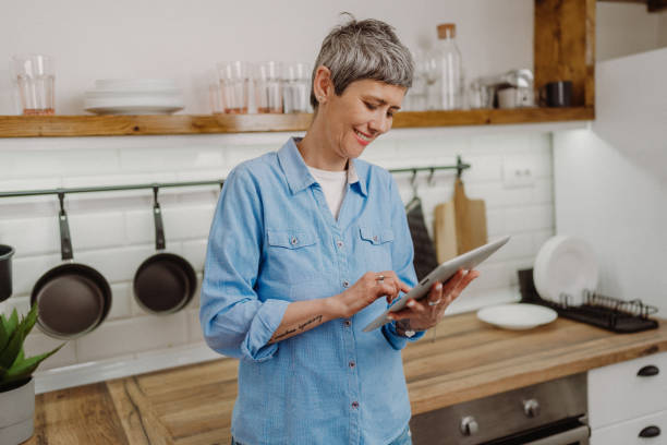 istock Senior woman standing and holding her digital tablet 1480641716