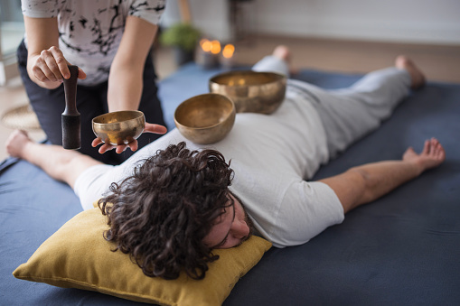 Young man enjoying Shiatsu massage with Tibetan singing bowls for his insomnia