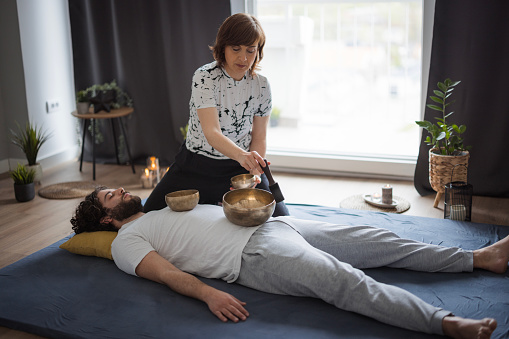 Man relaxing when having a treatment including Tibetan singing bowls during massage