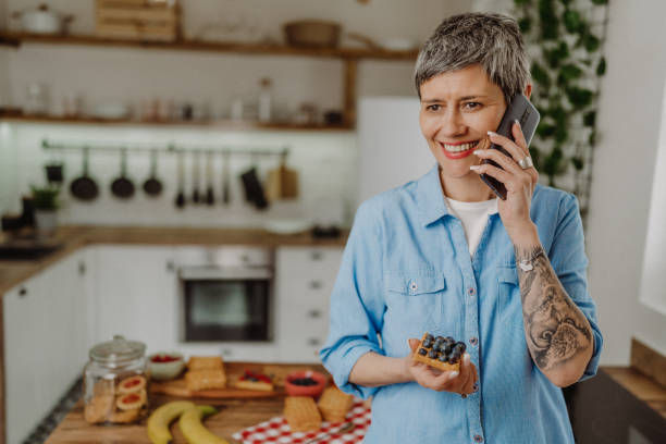 istock Mid age woman eating breakfast while talking on the phone 1480644358