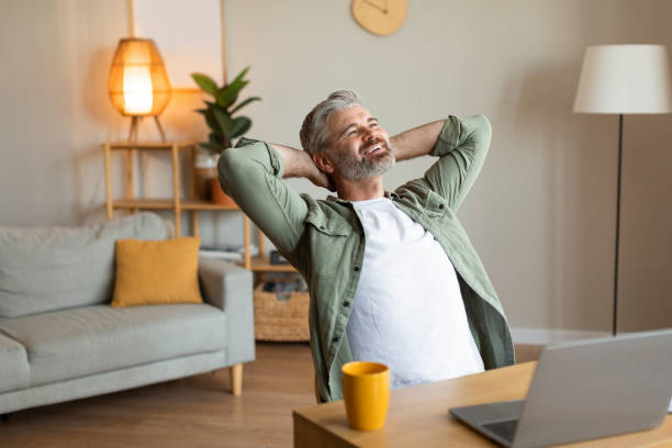 istock Satisfied happy relaxed elderly caucasian male sits at table with computer, rest in living room interior 1480645816