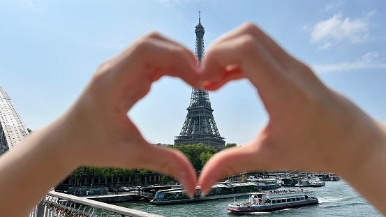 a beautiful teenage girl looks into the frame leaning against the backdrop of the Eiffel Tower She smiles and seems to be showing come here great advertisement for a trip to Paris. High quality photo