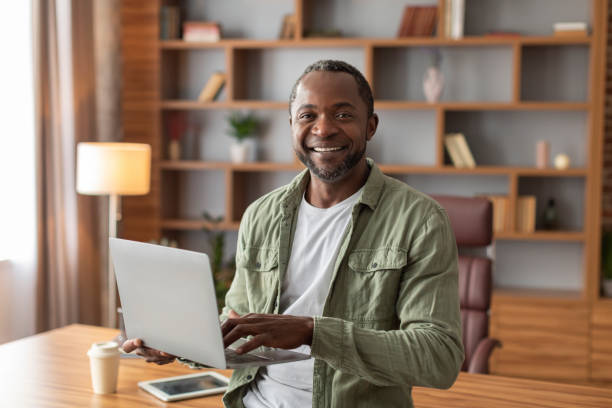 istock Smiling attractive mature black male manager with laptop work, make presentation and look at camera 1480648105
