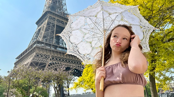 tender close-up can be used for any advertisement there is a place for text. girl with an openwork umbrella the sun walks from the Eiffel Tower against the backdrop of a bright green tree