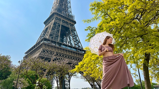 tender close-up can be used for any advertisement there is a place for text. girl with an openwork umbrella the sun walks from the Eiffel Tower against the backdrop of a bright green tree