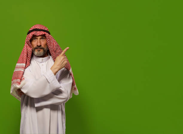 istock mature Muslim man in a traditional dishdasha points his finger towards copy space symbolizing concept of Sharia law, the Islamic legal system based on teachings of Quran and Hadith. authority, leadership, and principles of justice and ethics within the l 1480649793