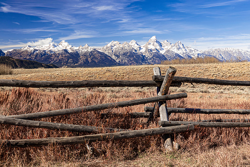Autumn landscape of a ranch corral wood fence and meadow with a panoramic view of the Grand Teton Mountain Range in Grand Teton National Park Wyoming.