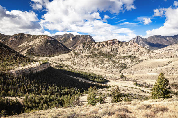 view from the top of the Chief Joseph Byway lookout in the rugged Rocky Mountains of northwest Wyoming with blue sky and white clouds.