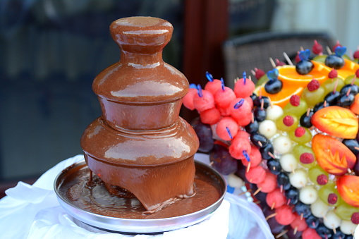 chocolchocolate fountain and carving from different fruits on a glass table. High quality photo