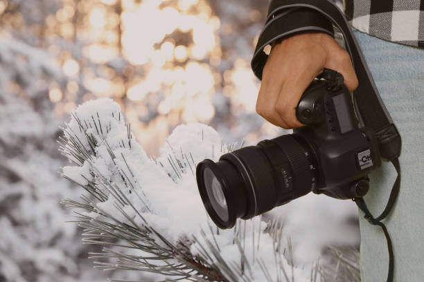 istock Professional photographer with modern camera and blurred view of snowy forest, space for text 1480657542