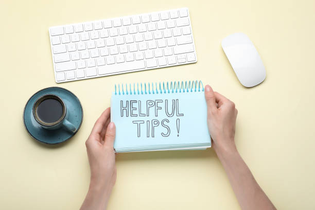 istock Woman holding notebook with phrase Helpful Tips at beige table, top view 1480657554