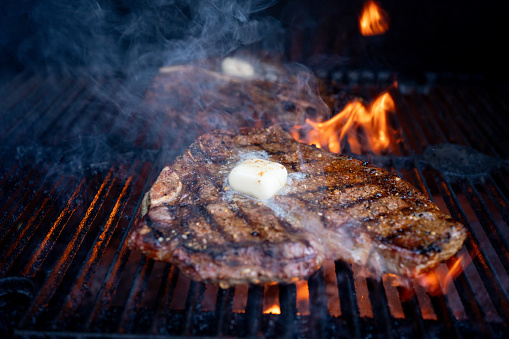 Juicy T-bone beef steak, flame-grilled to perfection, and topped with a generous knob of butter, is a classic and mouth-watering steakhouse favorite