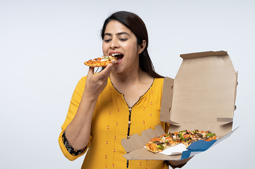 Photo of pizza held by smiling young woman against white background