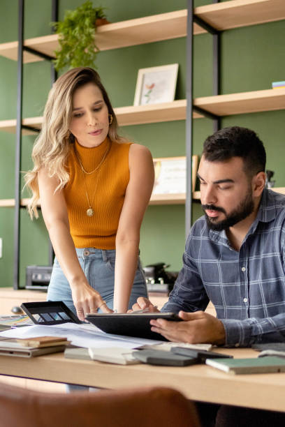 istock Two architects looking at blueprints on a tablet at an office desk 1480659574