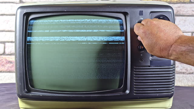 Man Hand Tuning Old Television With Gray Interference Screen Channel