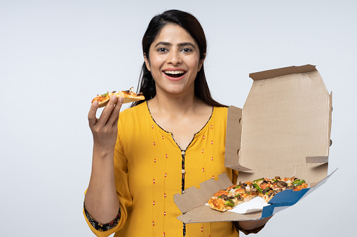 Photo of pizza held by smiling young woman against white background