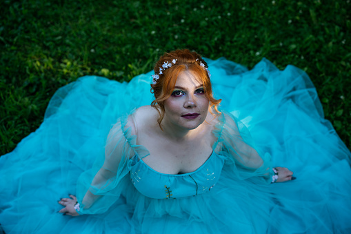 Top view of redhead young bride with acne in blue dress in park. Wedding or prom photo.