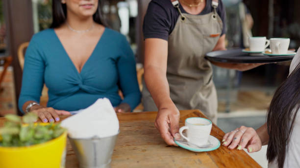 cameriera che porta ai clienti il loro ordine di caffè al tavolo di un caffè sul marciapiede - service occupation candid small business carrying foto e immagini stock