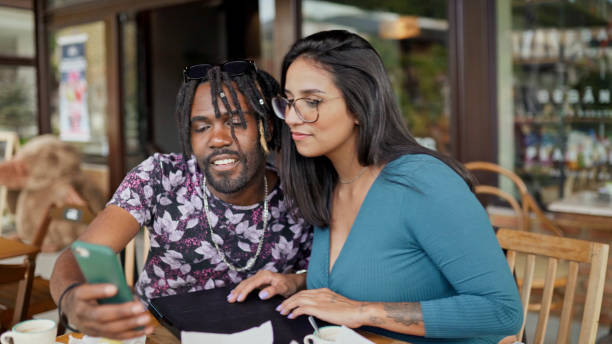 istock Friends looking at a phone outside at a cafe table 1480662295