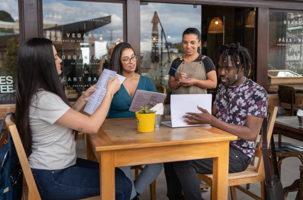 istock Friends giving a server their order while sitting at a cafe table outdoors 1480662325