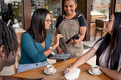 Waitress accepting payment by card at coffee shop