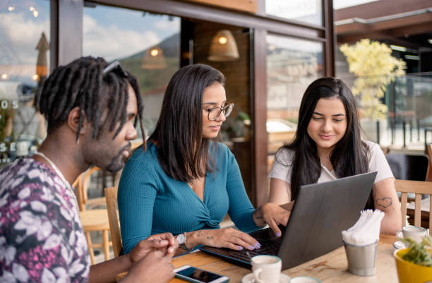 istock Young friends working on a laptop over coffee at a cafe table outside 1480662356