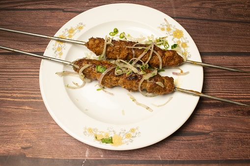 Chicken Seekh kabab or Shikh kebab tikka served in dish isolated on wooden table top view indian spices food