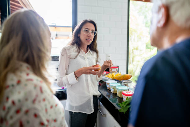 Nutritionist organizing meal plans for a senior couple during a diet consultation Young nutritionist discussing meal planning with a senior couple during a diet consultation in their kitchen at home nutritionist stock pictures, royalty-free photos & images