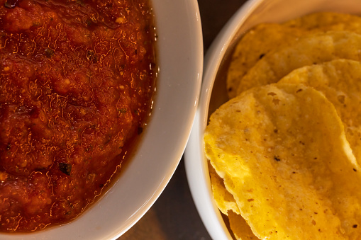 Overhead view of red salsa and tortilla chips. Extreme close-up view.