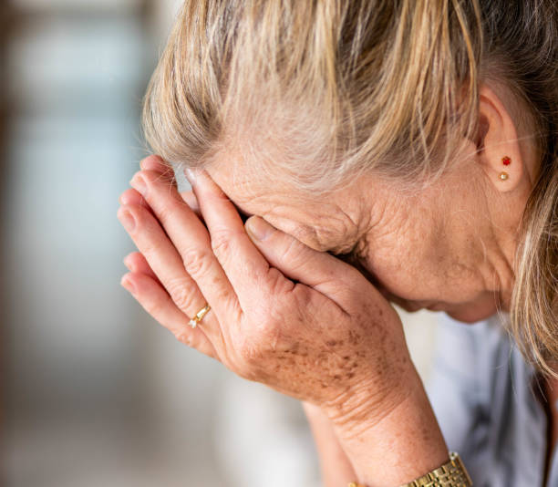 istock Senior woman with depression sitting with her head in her hands 1480671247
