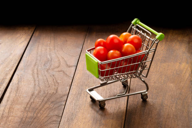 Small organic juicy fresh tomatoes in shopping cart as conceptual image to buy  online using internet.