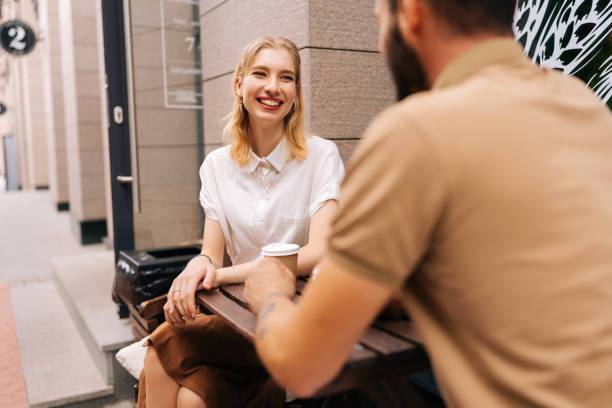 heureux jeune couple amoureux prenant un café ensemble et profitant de la vie assis à table dans un café de rue le jour d’été. vue de dos d’un homme méconnaissable. - beautiful communication enjoyment happiness photos et images de collection