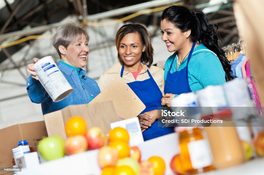 Team di volontari che lavora con donazioni di cibo in donazione center - Foto stock royalty-free di Volontario