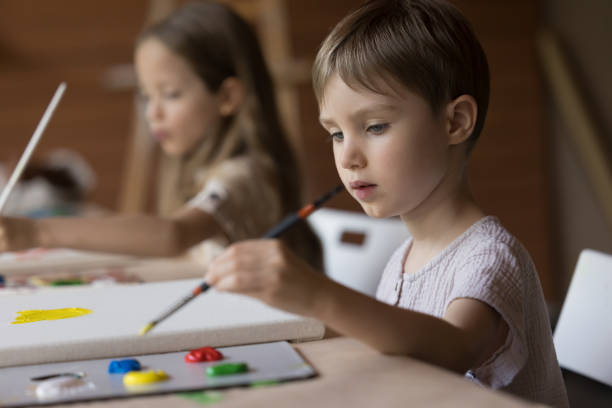 istock Serious engaged kid boy painting on canvas, using paintbrush 1480690705