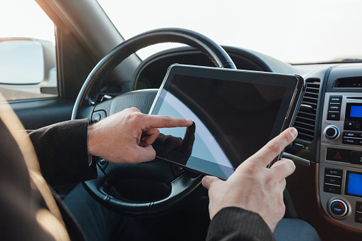 Driver adjusts the navigation on tablet in car