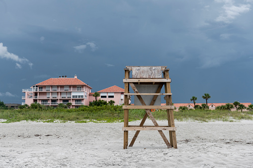 This is a photograph of an empty wooden lifeguard chair Cocoa Beach, Florida before the rain storm.