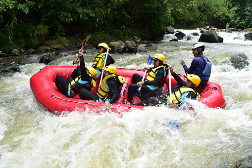 West Java, Indonesia - April 8, 2023 : a group of tourists playing rafting on a fast-flowing river, during the day.