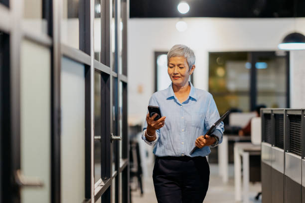 Senior Asian businesswoman using smartphone in office