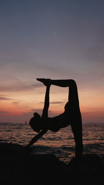 Asian woman exercising yoga on the beach by the sea